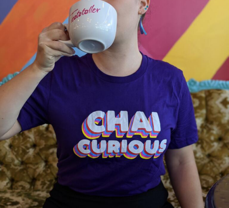 Woman in purple t-shirt that says chai curious